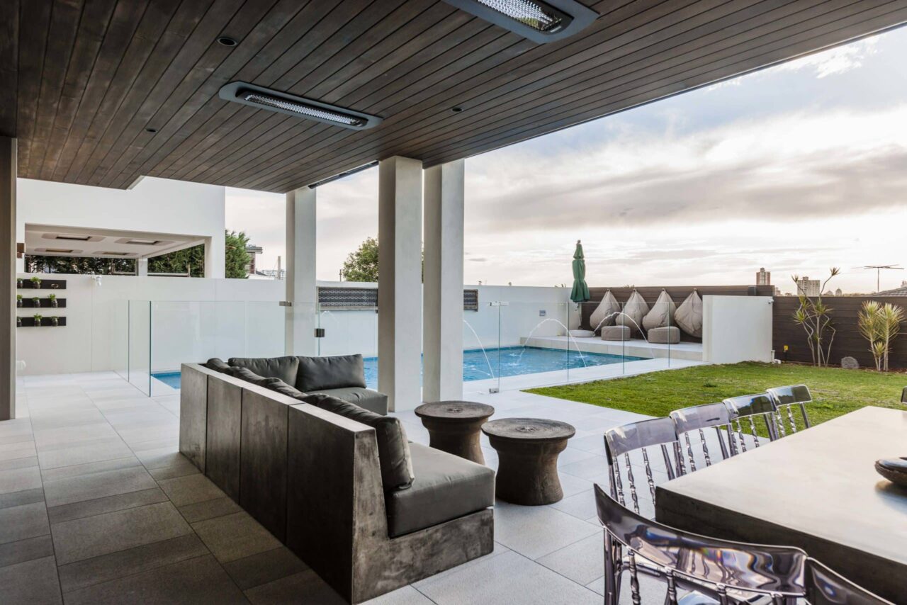 Modern outdoor lounge with recessed ceiling heaters, sleek fire designs, and poolside seating for a stylish backyard retreat.